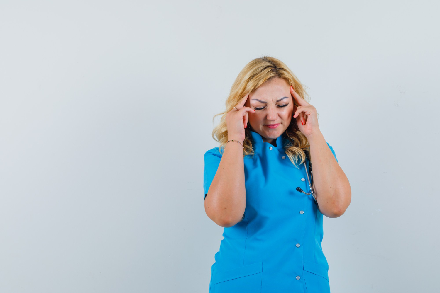 A stressed-out home carer rubbing her temples. A stressed-out home carer rubbing her temples.
